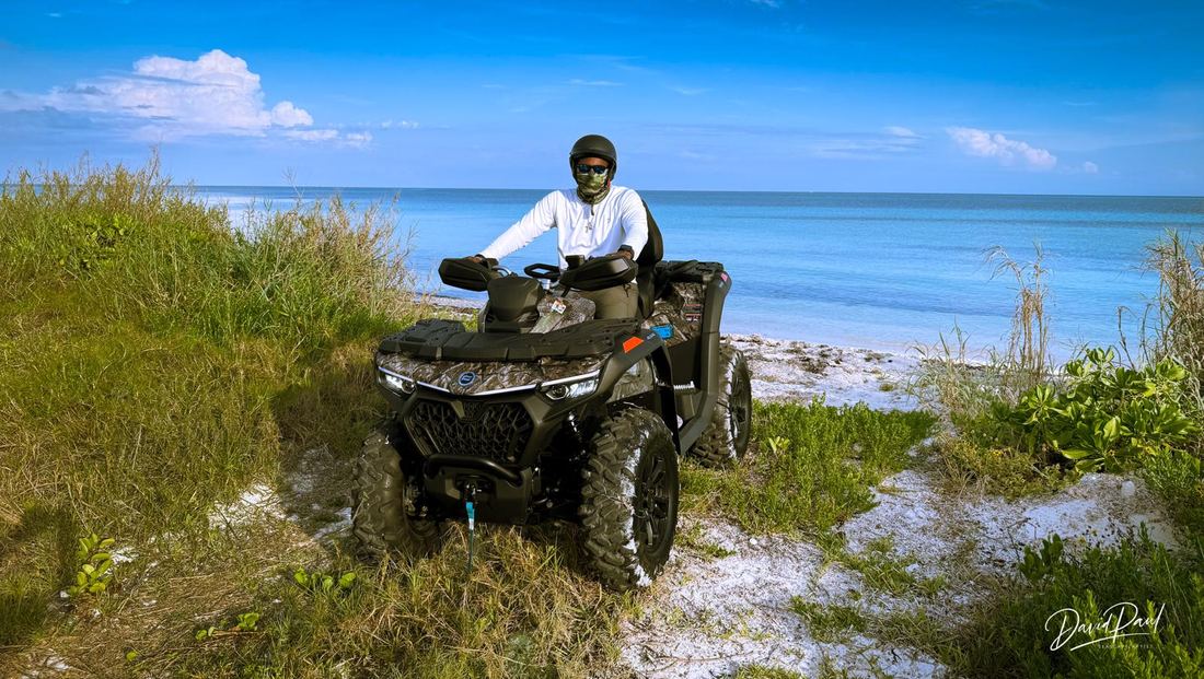 Rider on an ATV at the edge of a white sand beach