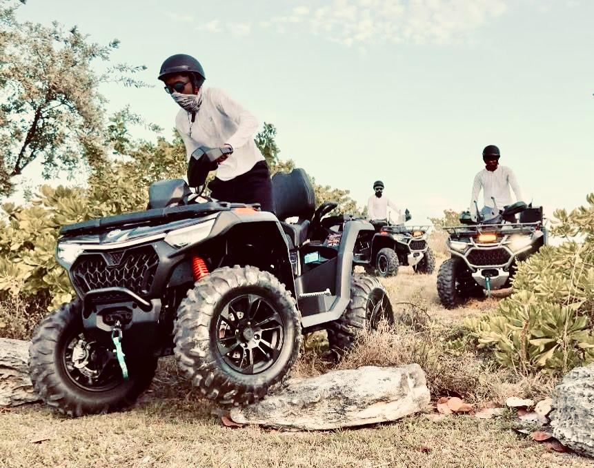 Riders on ATVs crossing rocky ground