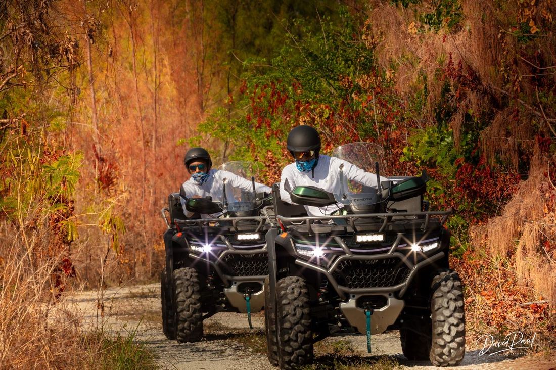 Two riders on ATVs on a colorful island trail